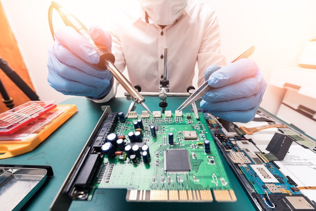 Forensic bench: gloved hands probing a circuit board