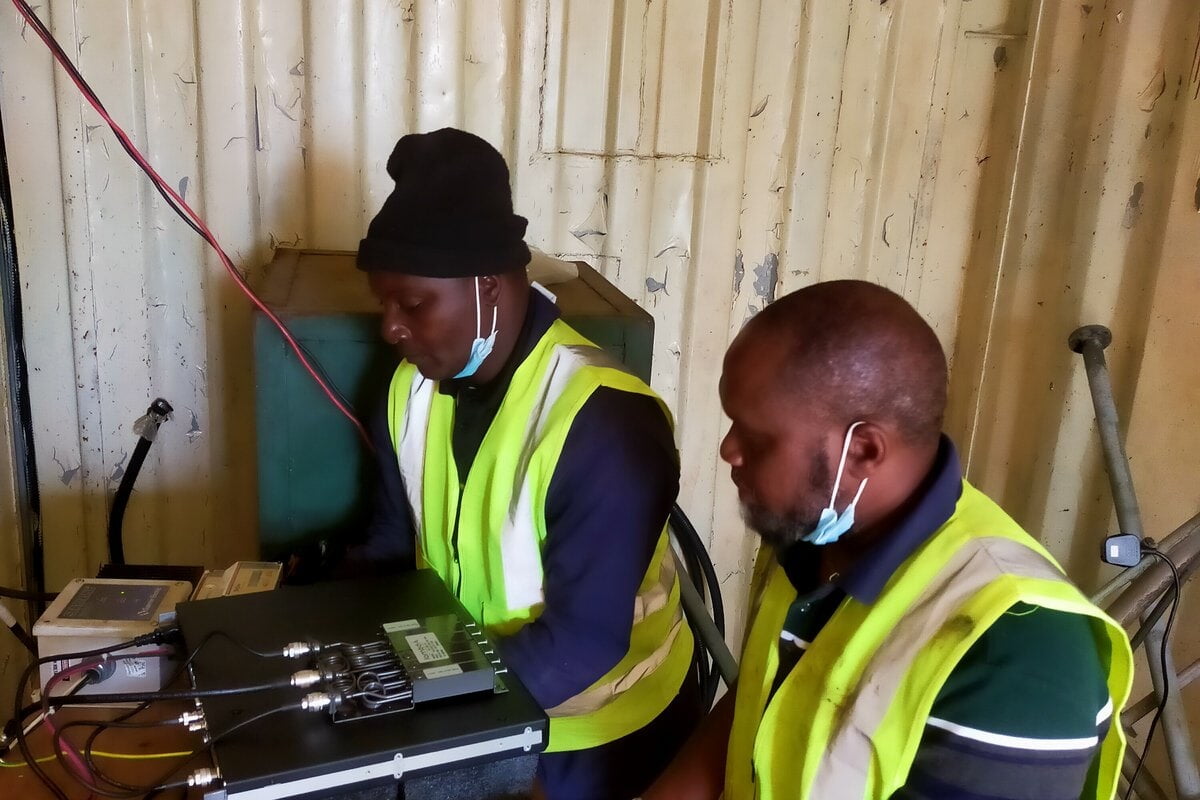 Two BCE technicians programming equipment at a site shelter